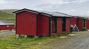 SkarsvågHytte Camp Nordkapp - Red的前面停着一辆摩托车的红楼