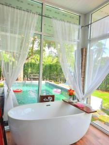 素叻阿曼特拉民宿度假村的设有一个大窗口的客房内的白色浴缸