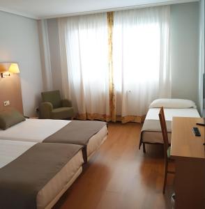 桑坦德圣米仑酒店的酒店客房设有两张床、一张书桌和一个窗户。