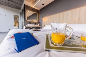 卡马里尼亚斯Hospedium Hotel Devalar Do Mar的床上的托盘,上面放着一杯橙汁和一本书