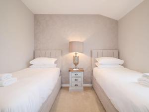 伍德布里奇Woodbridge Penthouse的卧室设有两张单人床,卧室配有床头灯。