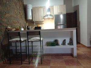 CepedaCasa Rural El Turuterro的厨房配有带凳子的柜台和冰箱。