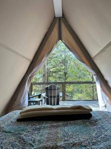 塔拉迪加Bohamia - Cozy A-Frame Glamp on 268 acre forest retreat的帐篷内带床的房间,设有窗户