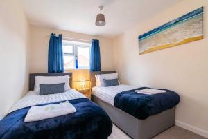 达宁顿堡4 Bed House in Castle Donington (EMA) with parking的配有蓝色窗帘的客房内的两张床