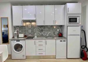 马德里Apartamento 4 personas的厨房配有白色橱柜和洗衣机。