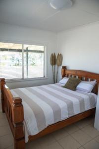 米申海滩Beach Haven的一间卧室配有带条纹棉被的床和窗户