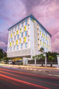 日惹Hotel Citradream Tugu Yogyakarta的一条白色的大建筑,街上有黄色的窗户