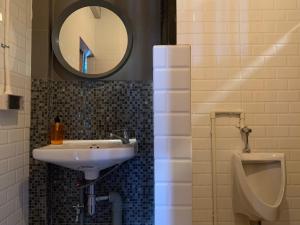 清莱Busket Hostel的一间带水槽、小便器和镜子的浴室