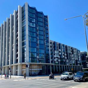 堪培拉Central Canberra City apartment with study and full amenities including parking的一座大型建筑,前面有汽车停放