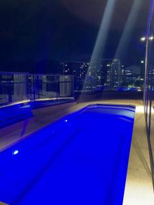 堪培拉Central Canberra City apartment with study and full amenities including parking的夜间建筑物屋顶上的蓝色游泳池