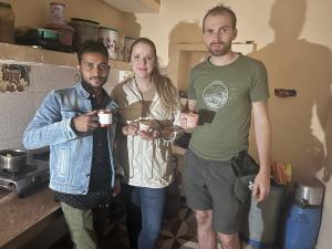 克久拉霍Hello India home stay的三人站在一个厨房里,拿着咖啡杯