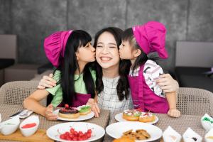 万隆万隆皇冠假日酒店的三位女孩在餐桌旁一边吃着食物一边低声 ⁇ 着脸