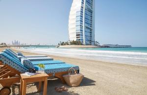 迪拜Jumeirah Beach Hotel Dubai的海滩上设有两张躺椅,大楼