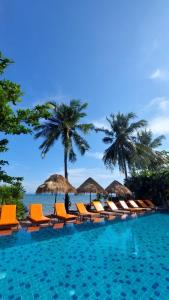 象岛象岛宁静度假村的一个带椅子和遮阳伞的游泳池以及大海