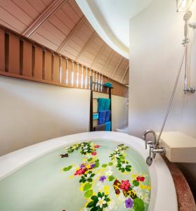 高兰Chada Lanta Beach Resort - SHA Extra Plus的浴室配有带鲜花的浴缸。