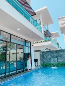 岑山Villa FLC Sầm Sơn Vị Trí Trung Tâm View Biển的女人站在游泳池旁的房子里