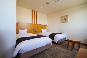 Ōmuta新加雅奥姆塔花园酒店的酒店客房设有两张床和一张桌子。