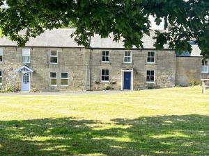 ElsdonBlue House Cottage的一座带蓝色门和草地的大型石头建筑