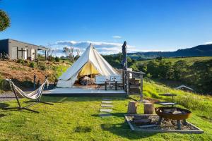 凯阿玛Cicada Luxury Camping的田野上的帐篷,配有两把椅子和一张桌子