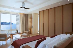 圣爱奥尼斯米科诺斯The Coast Bill & Coo -The Leading Hotels of the World的一间卧室配有一张床、一张书桌和一个窗户。