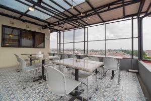 雅加达Urbanview Hotel Cantee Halim Perdanakusuma by RedDoorz的用餐室配有桌椅和大窗户