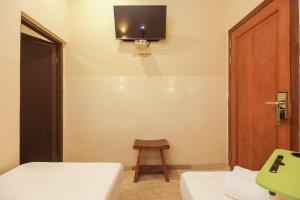 雅加达Urbanview Hotel Cantee Halim Perdanakusuma by RedDoorz的客房设有两张床和一台墙上的电视。