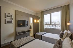 布卢梅瑙Slaviero Blumenau的酒店客房设有两张床和电视。