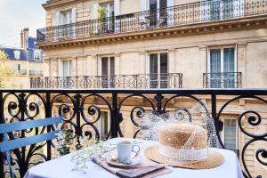巴黎Hôtel Sainte-Beuve的阳台上的桌子上挂着帽子,喝着咖啡