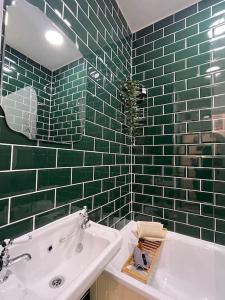 切斯特Hoole House- Bright and modern 2 bedroom house, close to Chester train station and the City Centre的绿色瓷砖浴室设有浴缸和水槽