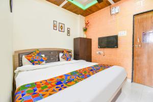 浦那FabExpress Vardhan Executive的一间卧室配有一张带彩色毯子的床