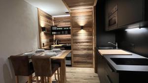 安塞热Les Cerfs - Appartement & Studio - ANZERE的厨房配有木制橱柜和桌椅