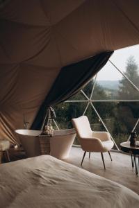 RichkaMandra Hills的帐篷内的1张床、1把椅子和1个浴缸