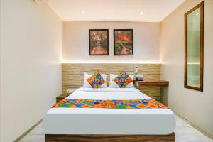 孟买FabExpress The Dream Residency的卧室配有一张带彩色枕头的大型白色床。