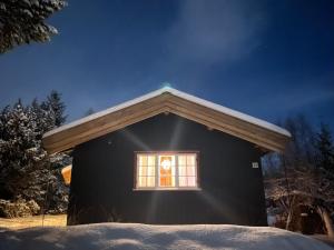 奥普达尔Charming Mountain Cabin的一间黑色的小房子,在雪中设有窗户
