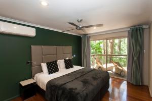 谭伯连山Songbirds Rainforest Retreat的一间卧室设有一张带绿色墙壁和窗户的床。