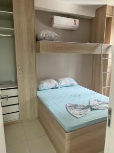 瓜鲁雅Apes Enseada Guarujá的小房间设有一张带蓝色床单的双层床