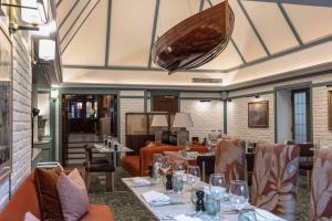 亨利昂泰晤士The Relais Henley的餐厅设有桌椅,天花板上悬挂着一条船