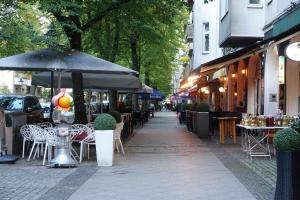 柏林Ferienunterkunft im Tegelhaus的人行道配有桌椅和雨伞