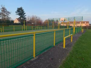 ÉtervilleZénithouse的一条有黄色杆和篮球架的围栏