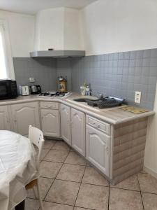 CorbarieuCharmant petit appartement的白色的厨房设有水槽和炉灶。