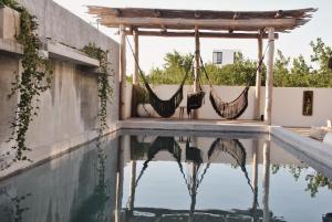 奥尔沃克斯岛Boutique Hotel EL NIDO Holbox的一个带吊床的游泳池,吊床悬挂在凉棚上