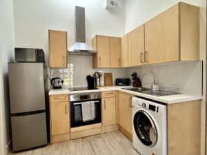 BargrennanThe Coorie的厨房配有木制橱柜、洗衣机和烘干机