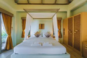 班拉克海滩Punnpreeda Beach Resort - SHA Plus Certified的一间卧室配有一张带橙色窗帘的大型白色床。