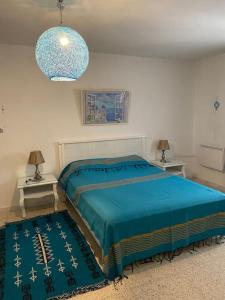 突尼斯Maison à El Omrane .的一间卧室配有一张床和两张带台灯的桌子。