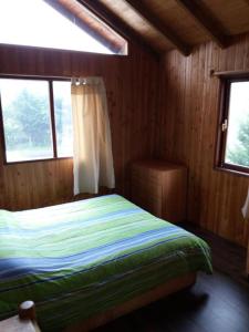 普孔Hostal Quillelhue的木制客房内的一间卧室,配有一张床