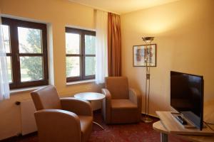 基姆湖畔普林Hotel Luitpold am See的酒店客房带椅子、电视和窗户。