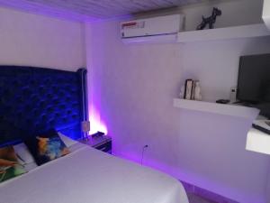 卡利Apartamento# 7 - 2 habitaciones Cali sur的卧室配有白色的床和紫色灯