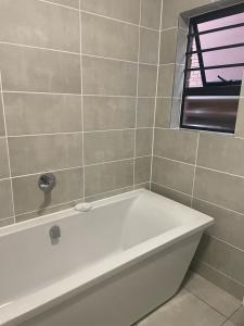 比勒陀利亚Blyde Beach Front Apartment Ground floor的带窗户的浴室内的白色浴缸