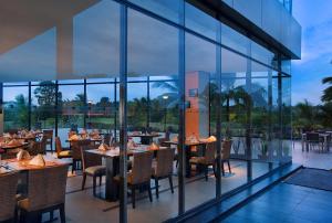 美娜多诺富特曼纳多高尔夫会议度假酒店的餐厅设有桌椅和窗户。