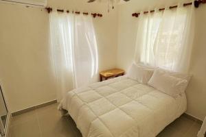 蓬塔卡纳Nice Apt in punta cana 7 minutes from airport , 10 minutes from the beaches的窗户客房内的一张白色床